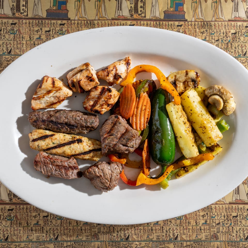King Tut's grilled meat platter with chicken, kofta, beef, and colorful vegetables on an Egyptian-themed tablecloth.